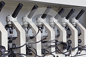 Cabinet with row of microscopes on shelve at biology