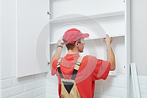 Cabinet shelf installation. Worker assembling furniture