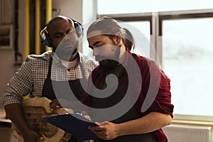 Cabinetmaker and apprentice inspecting lumber block for damages