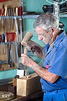 Cabinetmaker carving wood with a chisel and hammer