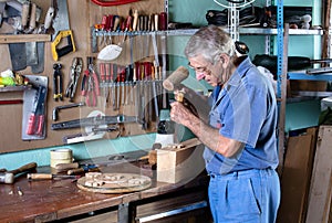 Cabinetmaker carving wood with a chisel and hammer in workbench