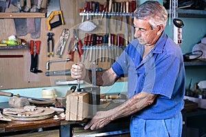 Cabinetmaker carving wood with clamp in workbench