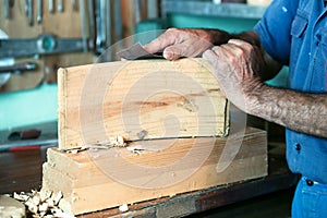 Cabinetmaker working with sandpaper in the bench in garage at ho