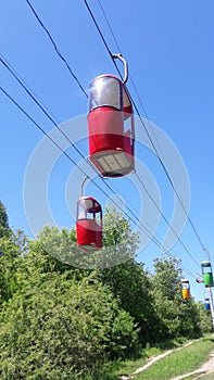 Cable car in the city, red cars on the background of the forest