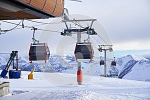 Cable car gondola at ski resort with snowy mountains on background. Modern ski lift with funitels and supporting towers