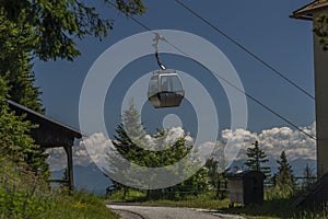 Cable car Kanzelhohe in green needles forest in summer sunny day