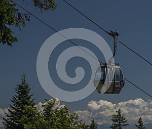 Cable car Kanzelhohe in green needles forest in summer sunny day