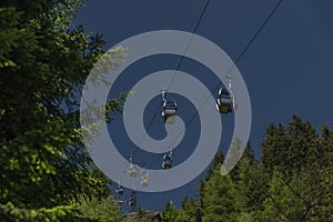 Cable car Kanzelhohe in green needles forest in summer sunny day