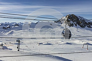 Cable car in the mountains and white snowy ski slopes. Snowy winter mountain background.
