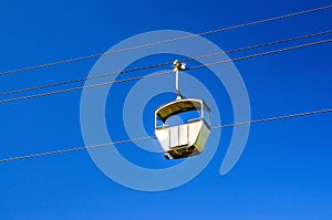 Cable car on rope of cableway, blue clear sky background in sunny summer day
