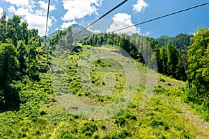 Cable car seats soar over beautiful mountains on a sunny day in Krasnaya Polyana
