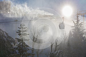 The cable car in the Sierra Nevada in a snow flurry. The sun shines as back light.