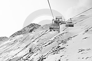 Cable car at a ski resort. Chairlift with skiers. Mountains covered with snow