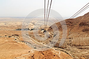 Cable car to ruins of palace and fortress Masada on Judaean Desert rock plateau with dead sea in the background, Israel