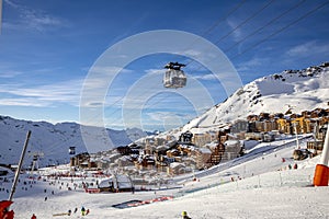 Cable cars hanging on the cables over mountains and Val Thorens village