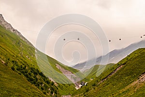 Cable cars between villages in northern Georgia in the Caucasus Mountains high over a valley with a glacier in the distance -