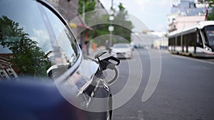 a cable at a city charging station charges an electric car in close-up. i. Plug-in module. the traffic is blurry