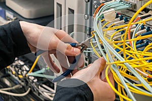Cable cutters in the hands of an internet connection installer. The specialist removes unnecessary wires in the data center.