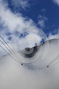 Cable lift through clouds to the mountain top