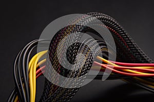 Cable snake skin. Black braided wires in bundle on black background. Braided Sleeving. Data line protection. Wire Flame-retardant