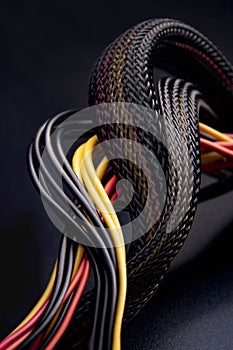Cable snake skin. Black braided wires in bundle on black background. Braided Sleeving. Data line protection. Wire Flame-retardant