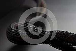 Cable snake skin. Black braided wires in bundle on black background. Braided Sleeving. Data line protection. Wire Flame-retardant