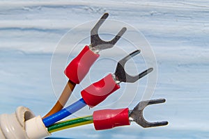 Cable with three electrical wires and terminals on blue background