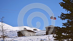 Cable way car in Goderdzi ski resort with old wooden houses in Adjara mountains in winter