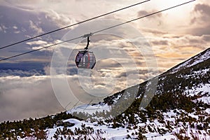 Cableway cabin above the clouds at sunset