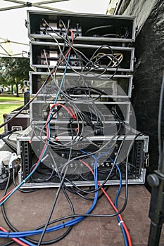 Cabling in multiple flight case racks with amplifier, effect devices, and radio microphone system on the desk of the sound mixer