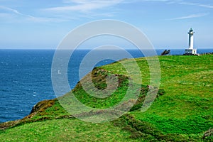 Cabo de Lastres lighthouse in Luces-Colunga, in Asturias (Spain), surrounded by green meadows on the Cantabrian Sea photo