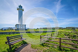 Cabo de Lastres lighthouse in Luces-Colunga, in Asturias (Spain), with a wooden bench in the foreground photo