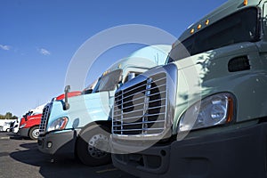 Cabs of big rigs semi trucks with grilles and headlight standing