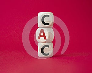 CAC - Customer Acquisition Cost symbol. Wooden cubes with word CAC. Beautiful red background. Business and Customer Acquisition