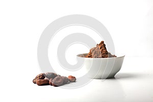 Cacao beans and a bowl of cacao powder isolated on white background