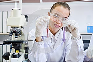 Cacausian female scientist in protective glasses looking and testing tube chemical