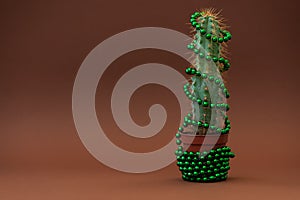 Cactus as Christmas tree with green ball garland on browm background. Christmas and New Year holidays celebration concept. Front photo