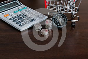 Caculator , Stack of coins , shopping trolley and compass with copay space