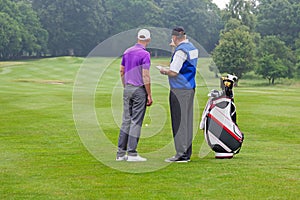 Caddy pointing out a hazard to golfer photo