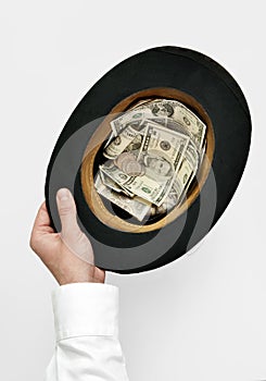 Cadger concept. Hand holding old top-hat with money
