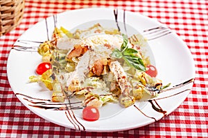 Caesar salad with chicken and bacon on white plate