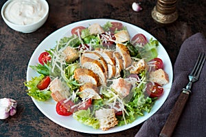 Caesar salad with chicken breast, croutons and parmesan sauce on a wooden