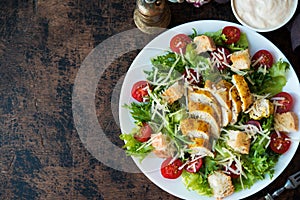 Caesar salad with chicken breast, croutons and parmesan sauce on a wooden table, a copy of space