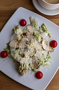 Caesar salad with chicken breast in a plate on the table. Appetizing dish. Close-up. Top view. Vertical