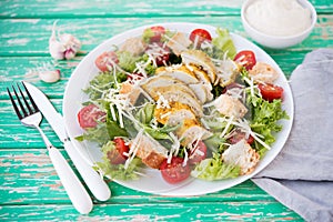 Caesar salad with chicken breast on a rustic background, tomatoes, parmesan, green salad and croutons