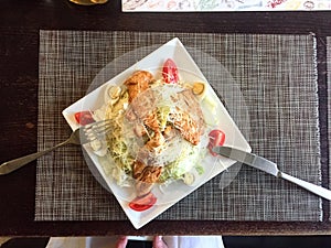 Caesar salad with chicken. cutlery on a white cloth napkin.