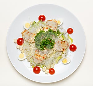 Caesar salad with chicken on a white plate and on a white background, top view