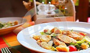 Caesar salad with croutons,eggs, cherry tomatoes and grilled chicken in a white plate on a table in a restaurant