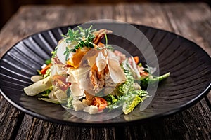 Caesar salad with fresh vegetables and crispy chicken on wooden background