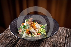 Caesar salad with fresh vegetables and crispy chicken on wooden background